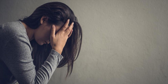 A person sitting with head in hand, appearing stressed or upset, against a plain background, reflecting the emotional challenges some people supported by RNID may face.