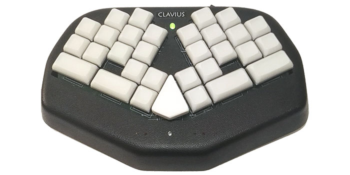 A split ergonomic keyboard labeled "Clavius," designed for palantypists, with two clusters of white keys and a single central white key, set in a black, polygonal base.