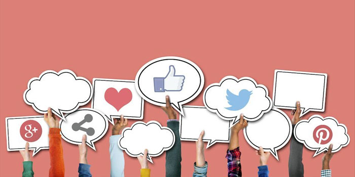 Several hands hold up speech bubbles and social media icons, including Facebook, Twitter, Pinterest, Google Plus, a heart, and a share symbol against a pink background—perfect for posts about captioning for business.