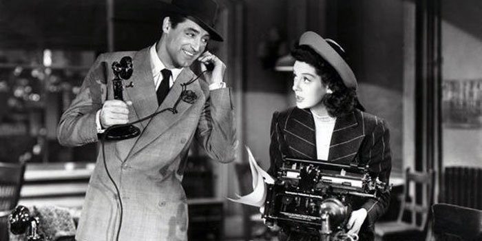 A man in a suit speaks on a rotary phone while a woman in a hat, possibly a stenographer, holds a typewriter; both are in an office setting with desks and papers.