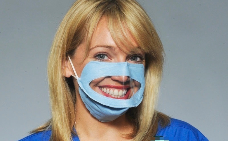 A woman wears a blue transparent face mask with a clear section over the mouth, allowing her smile to be visible.